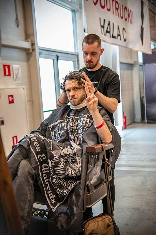 Barber zapewniający konsultacje i porady dotyczące pielęgnacji brody na swoim stoisku na MotoSession.