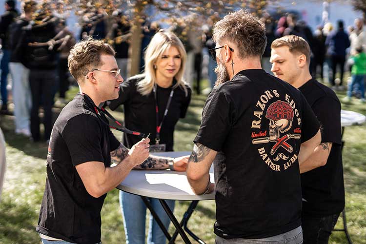 Ekipa Razor’s Edge rozmawia przy stoliku na zewnątrz – słońce, energia i roboczy luz.