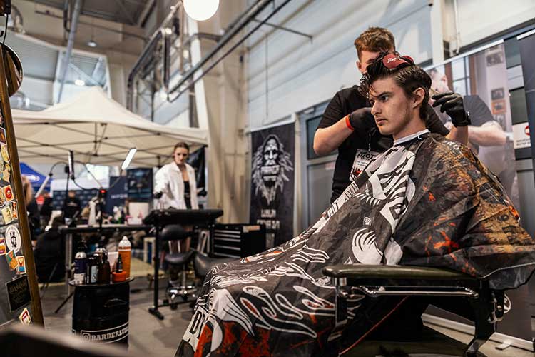 Barber przy fotelu z peleryną w stylu BORN TO RIDE – pełne skupienie i profesjonalizm.